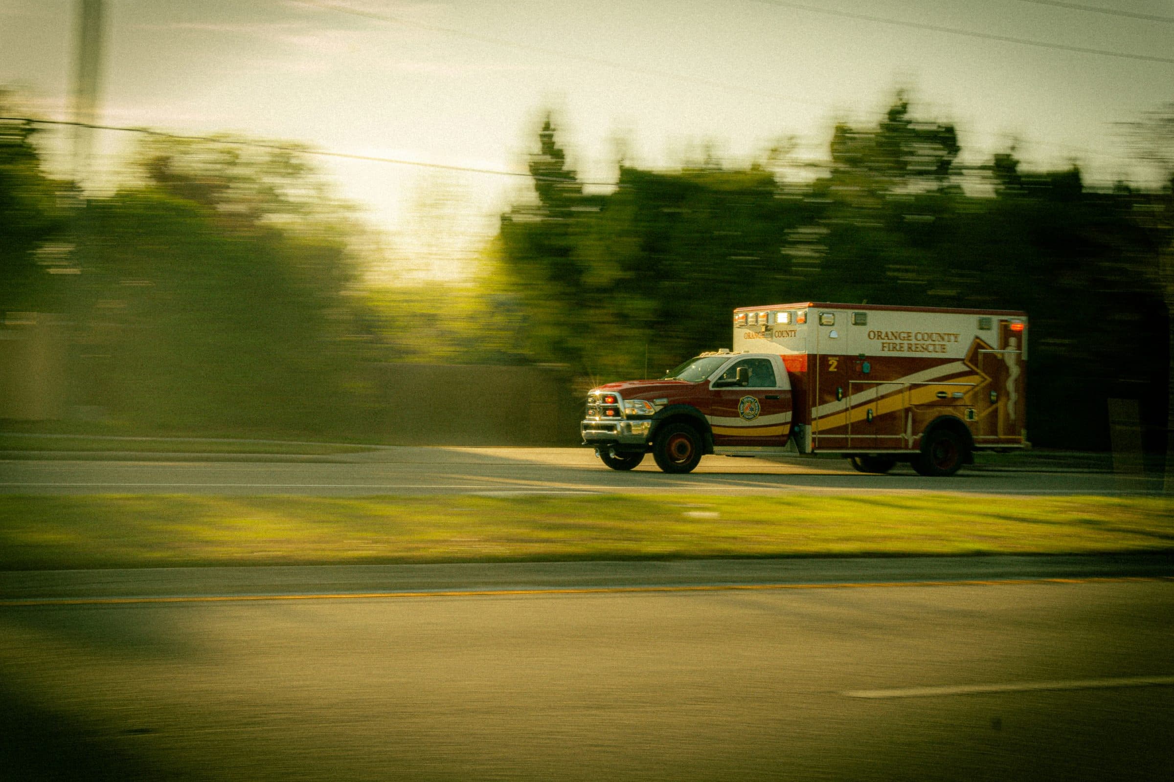 An ambulance travelling at speed at golden hour, background motion-blurred