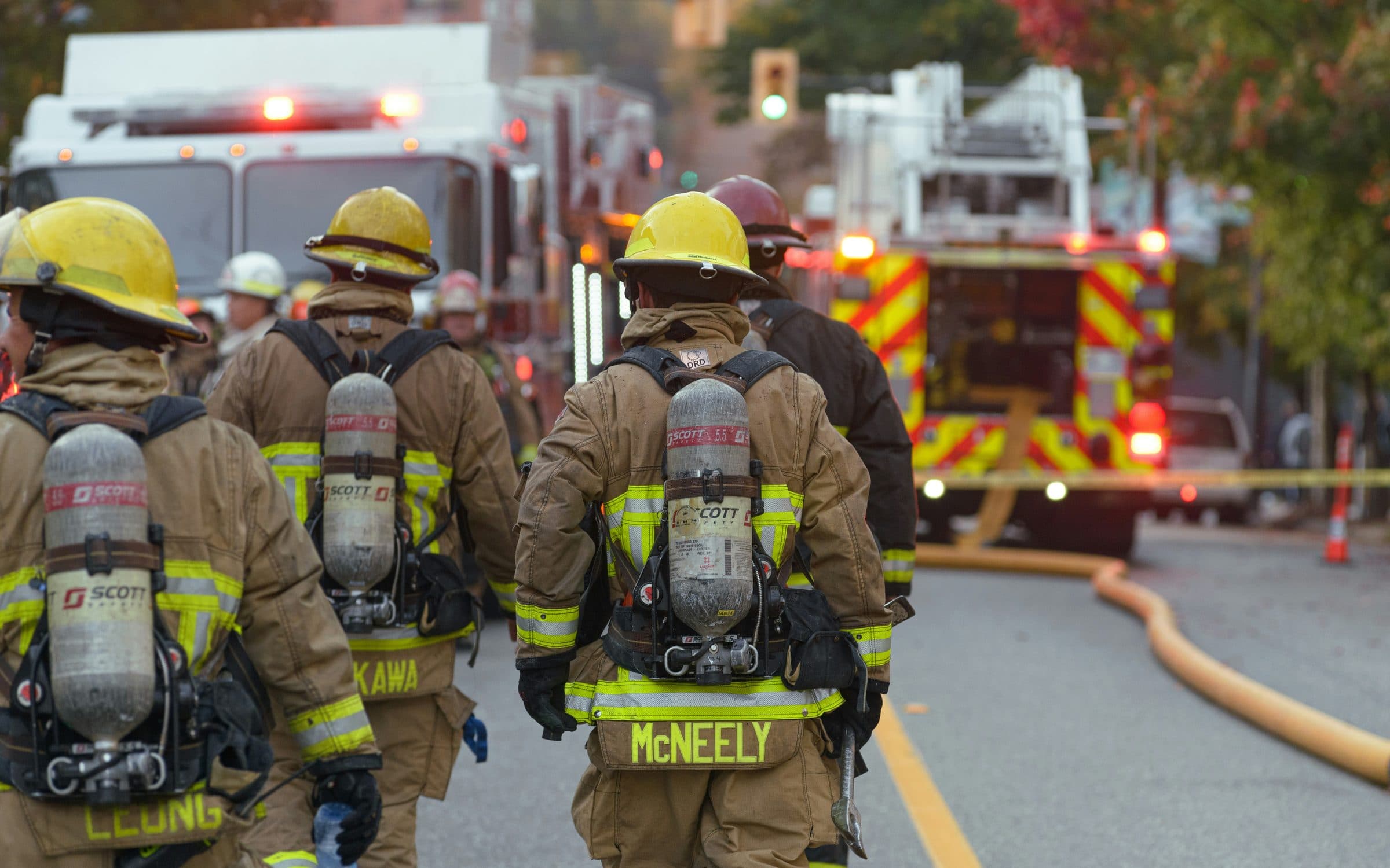 Firefighters in breathing apparatus walking toward apparatus on scene