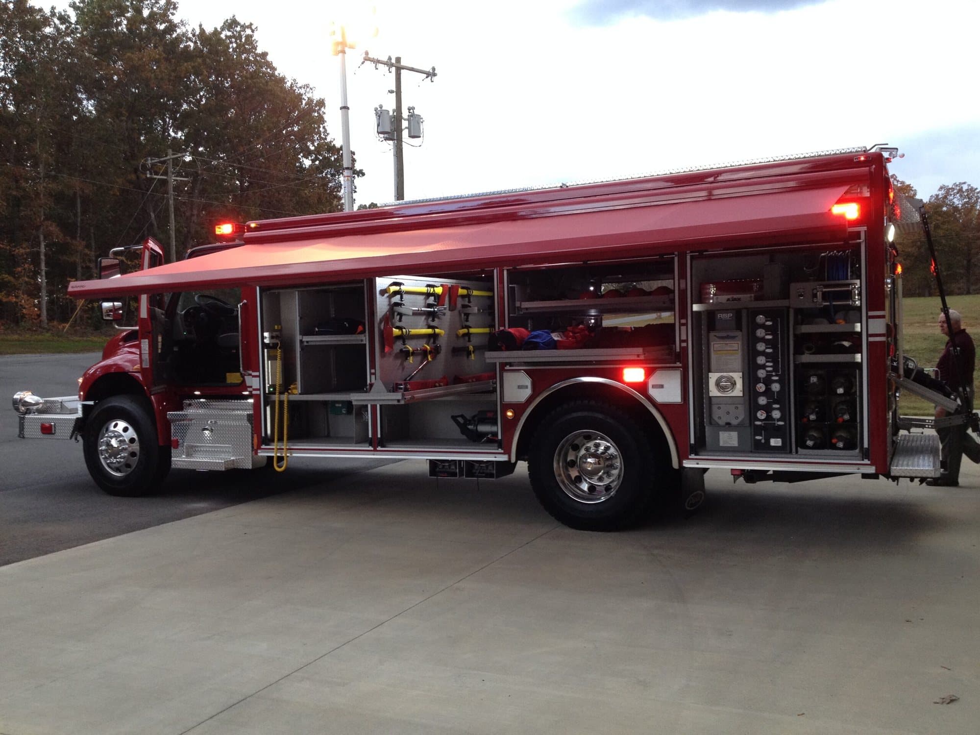 A rescue engine with its side compartments open, tools and hose racked inside